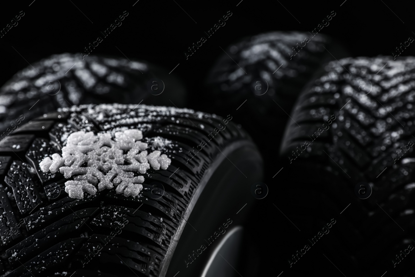 Photo of Snowy set of wheels with winter tires on black background, closeup. Space for text