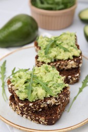 Photo of Delicious sandwiches with guacamole and arugula on plate, closeup