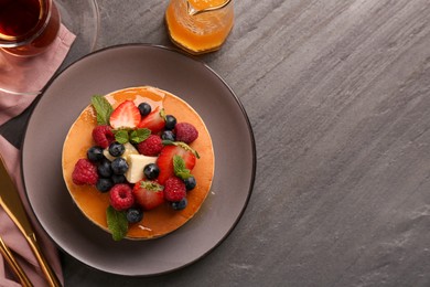 Photo of Delicious pancakes with fresh berries, honey and butter served on grey table, flat lay. Space for text