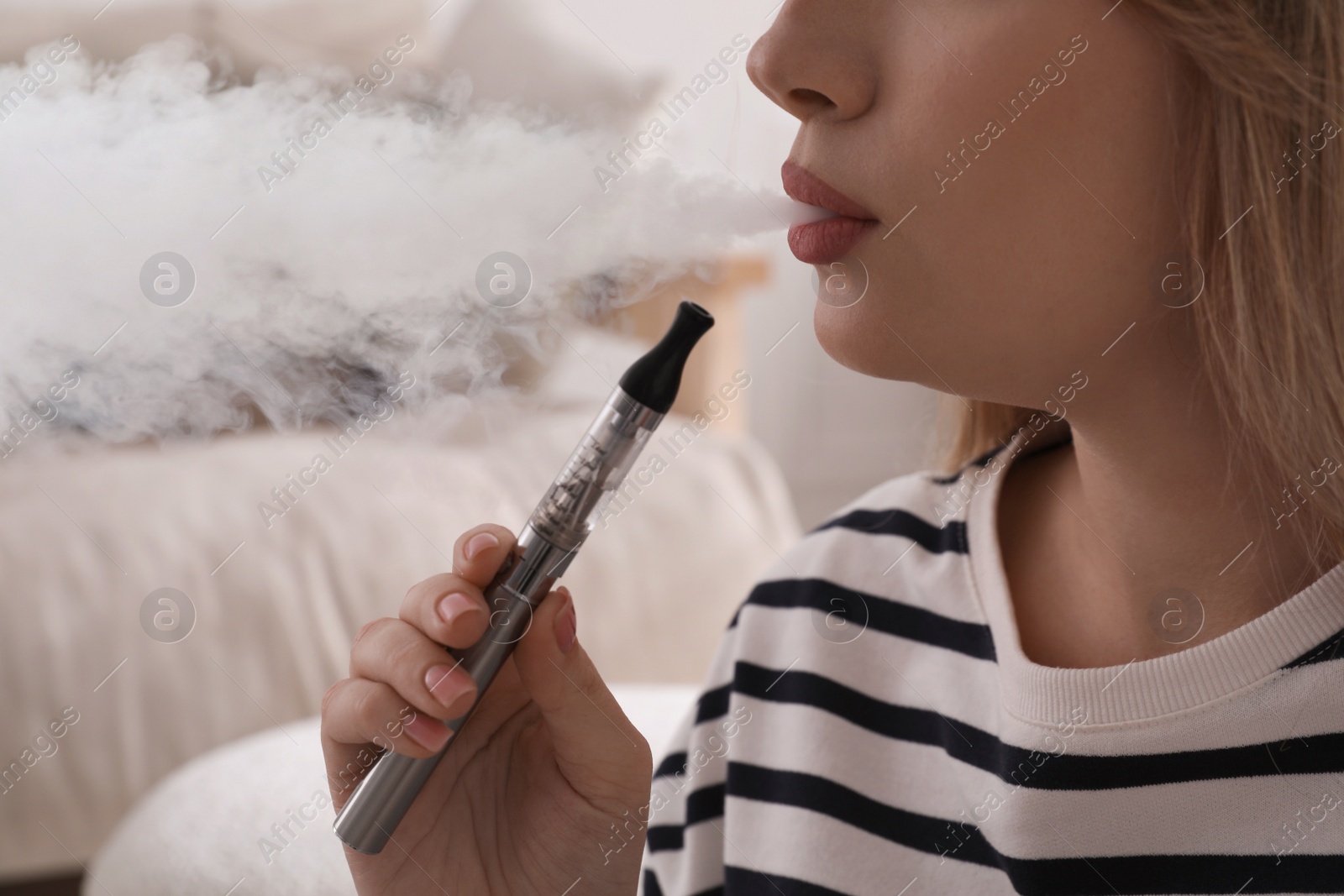Photo of Young woman using electronic cigarette at home, closeup