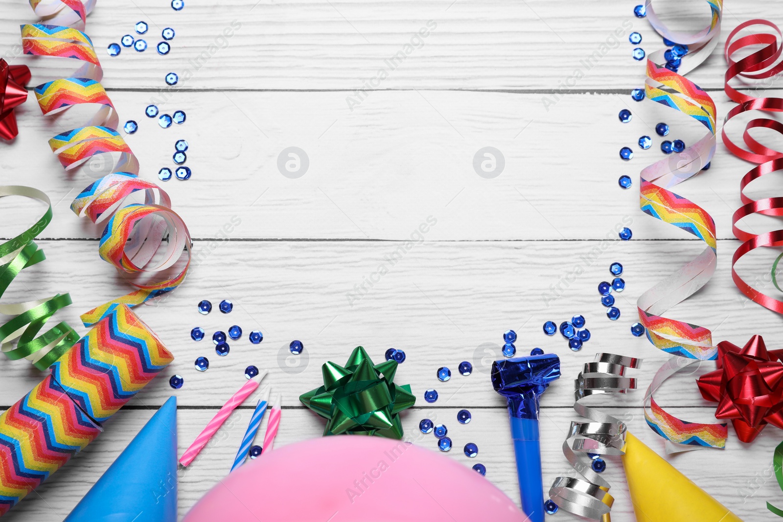 Photo of Flat lay composition with party items on white wooden table, space for text. Birthday celebration