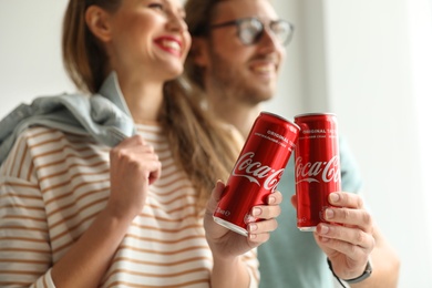 MYKOLAIV, UKRAINE - NOVEMBER 28, 2018: Young couple with Coca-Cola cans indoors