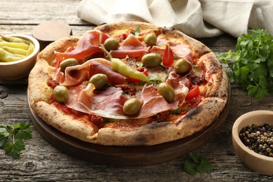 Tasty pizza and ingredients on wooden table