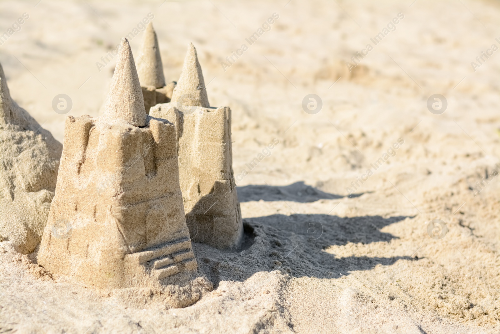 Photo of Beach with sand castle on sunny day. Space for text