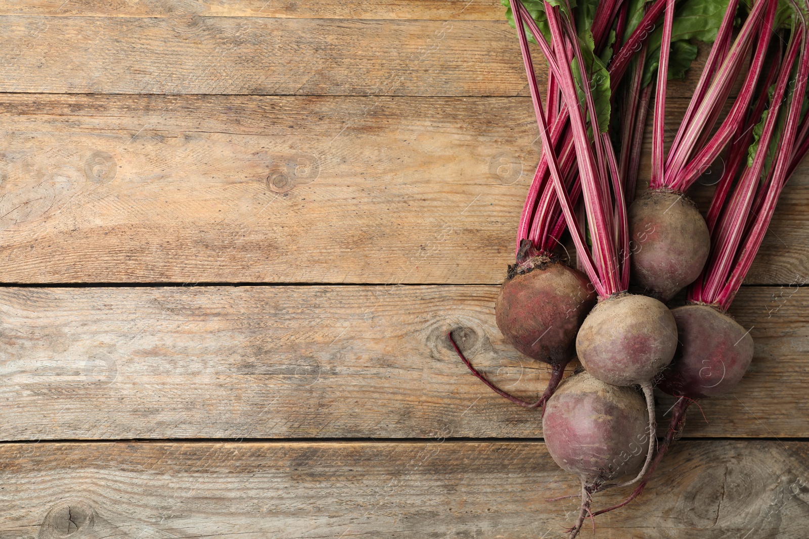 Photo of Raw ripe beets on wooden table, flat lay. Space for text