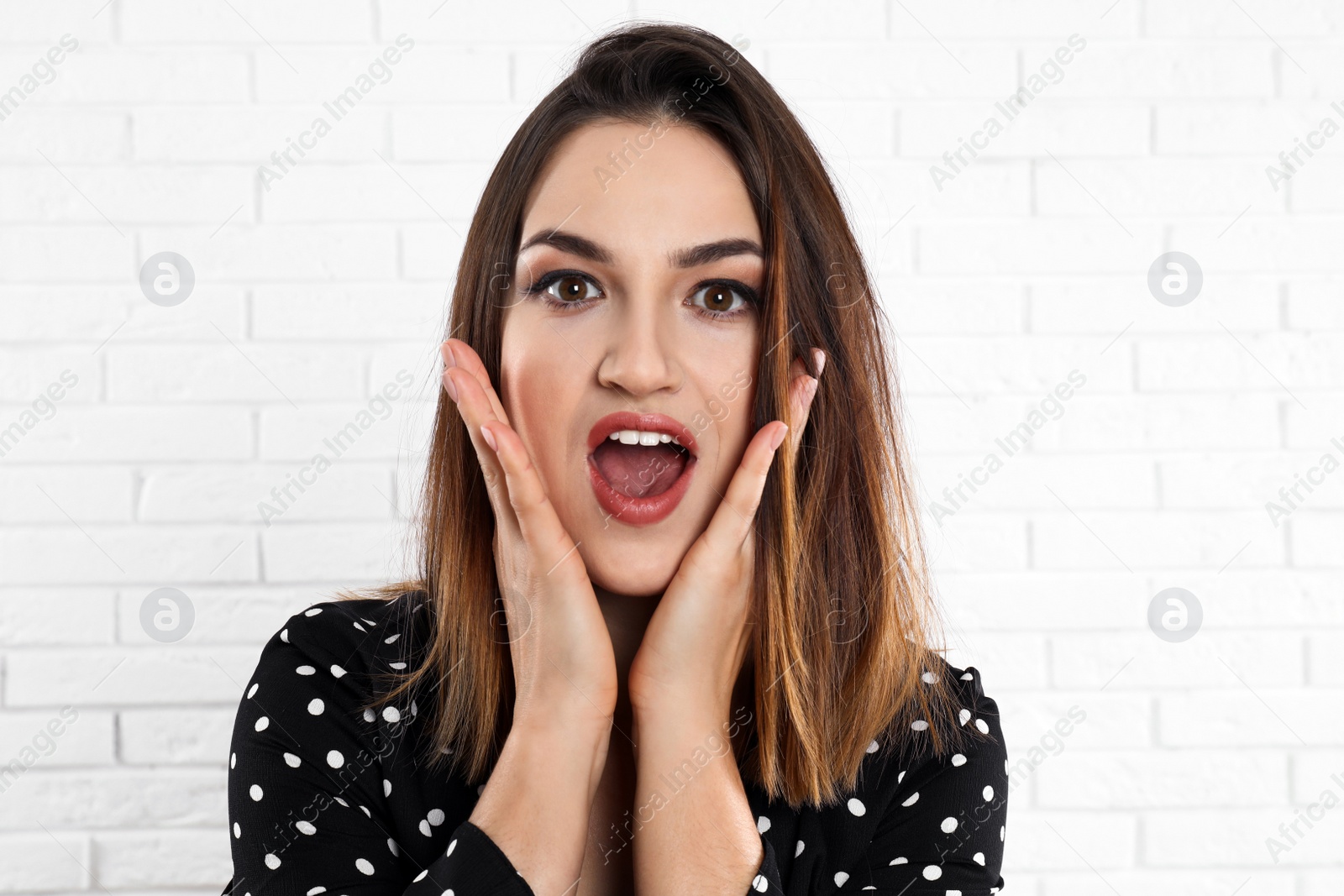 Photo of Beautiful young woman near white brick wall