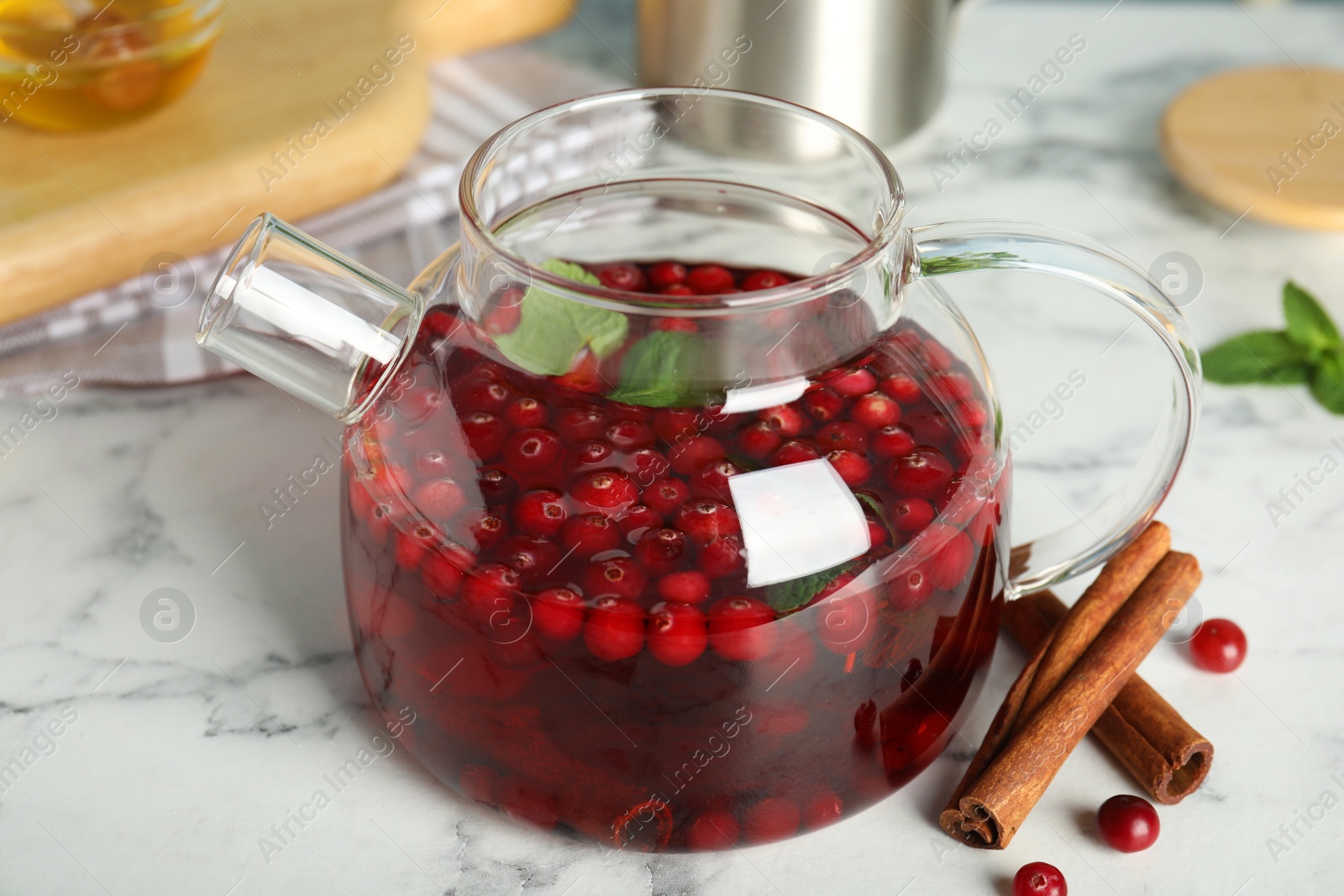 Photo of Tasty hot cranberry tea with mint and cinnamon on white marble table