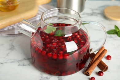 Photo of Tasty hot cranberry tea with mint and cinnamon on white marble table