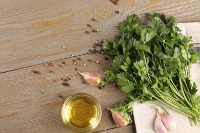 Photo of Bunch of raw parsley, oil, garlic and peppercorns on wooden table, flat lay. Space for text