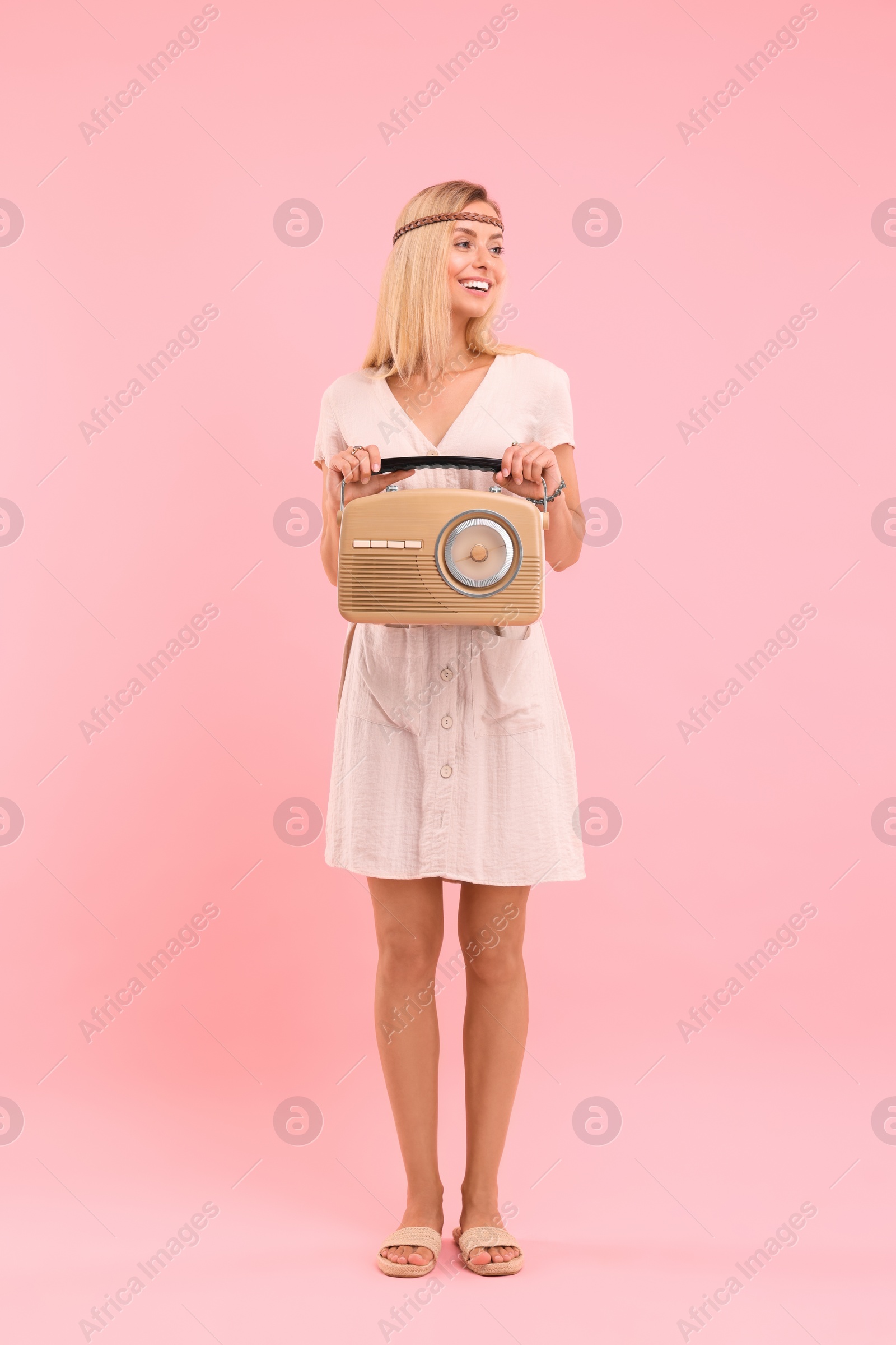 Photo of Happy hippie woman with retro radio receiver on pink background