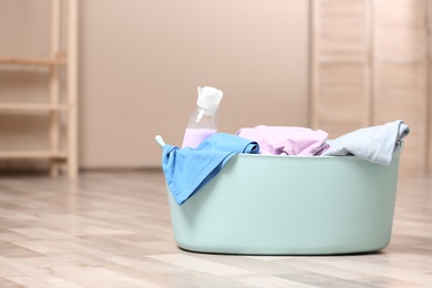 Laundry basket with detergent and dirty clothes on floor indoors. Space for text
