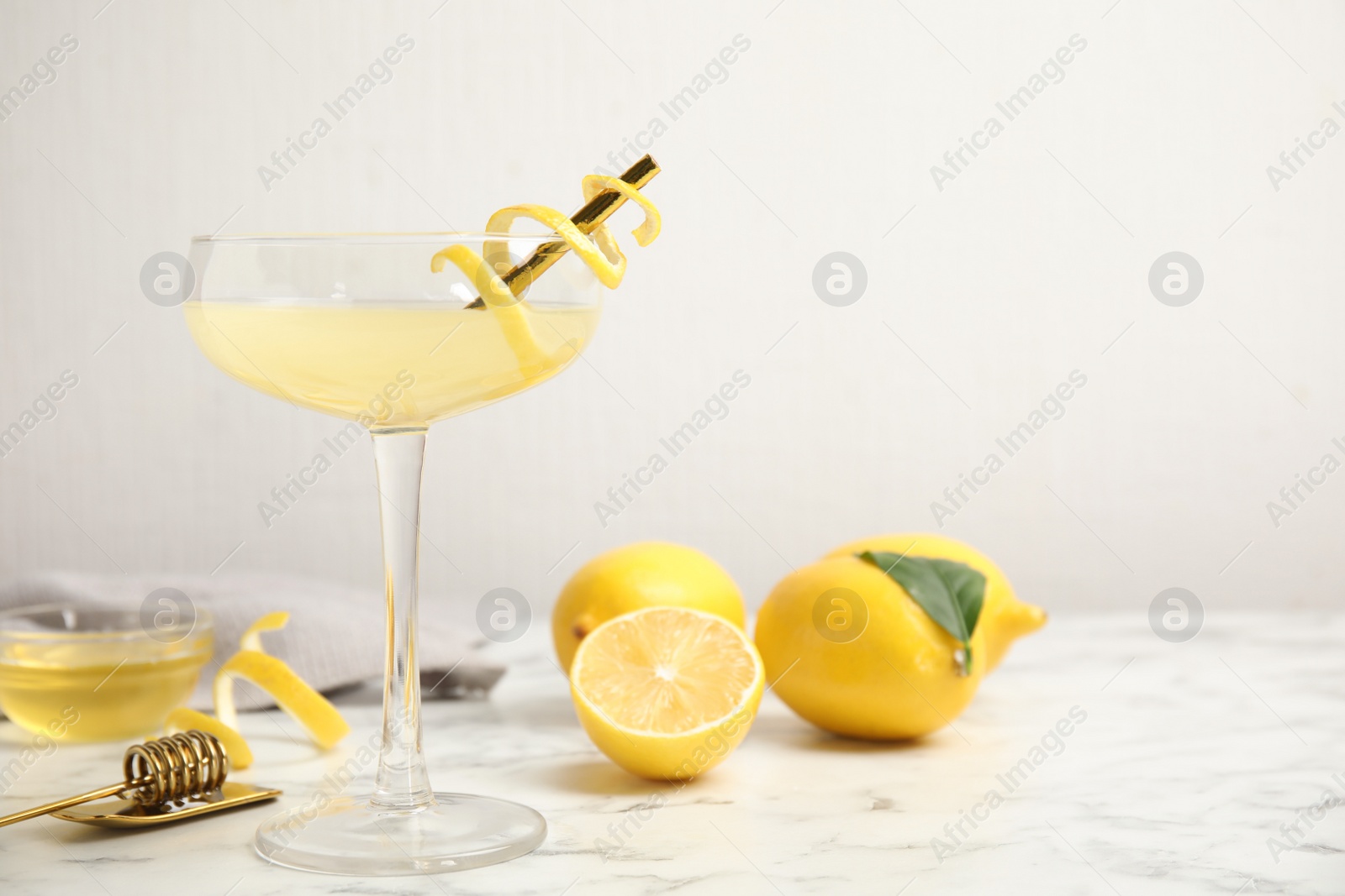 Photo of Delicious bee's knees cocktail and ingredients on white marble table. Space for text