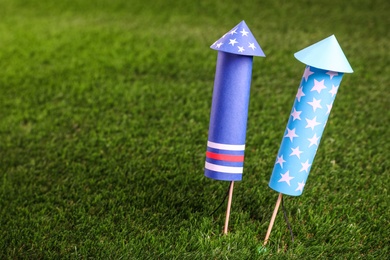 Firework rockets on green grass, closeup. Space for text