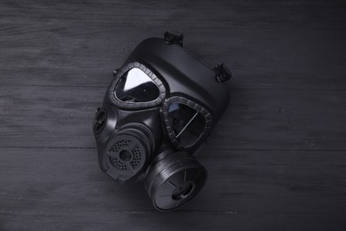 Photo of One gas mask on black wooden background, top view