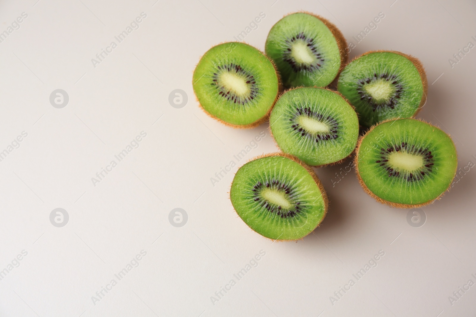 Photo of Halves of fresh kiwis on beige background, flat lay. Space for text