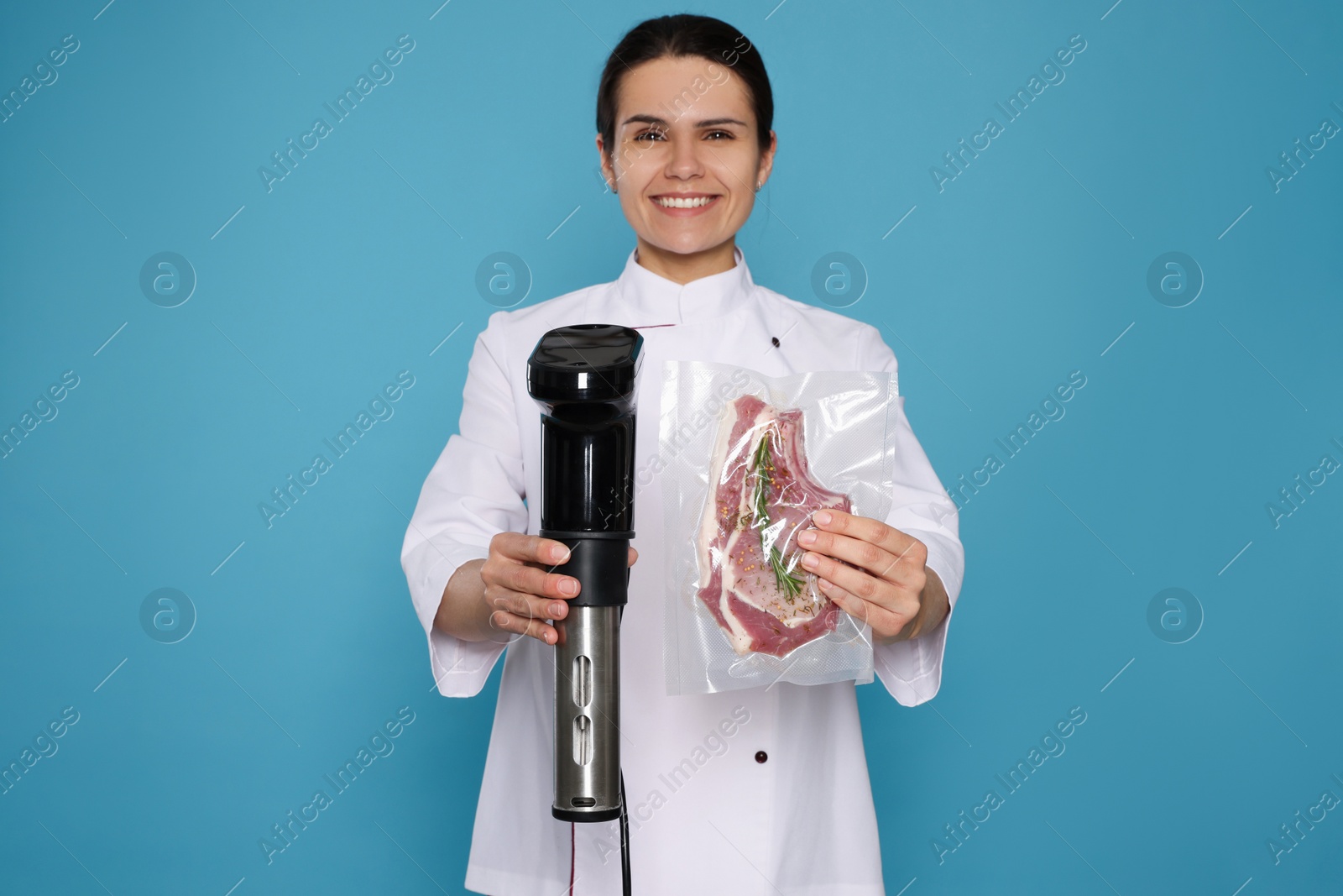 Photo of Chef holding sous vide cooker and meat in vacuum pack on light blue background