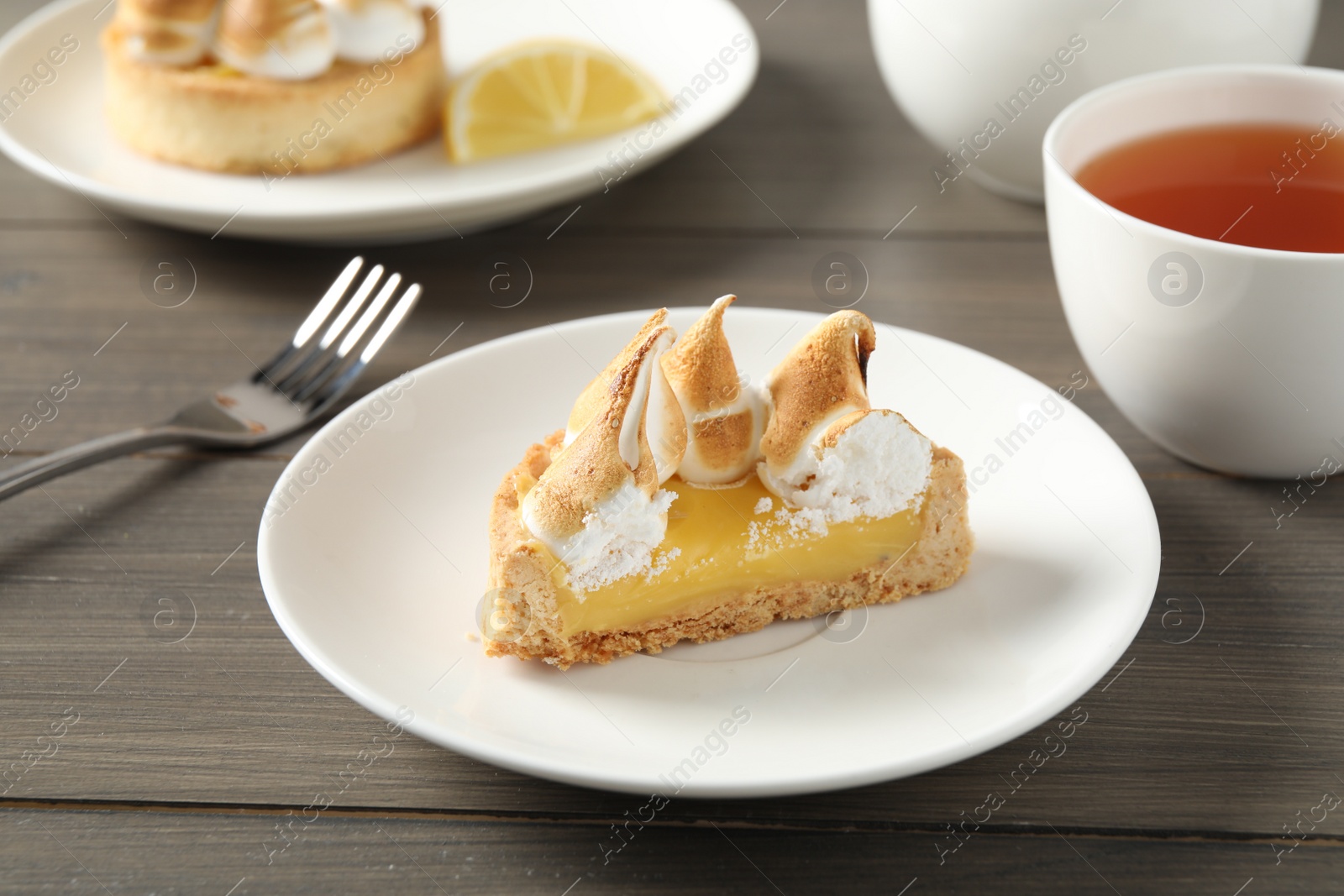 Photo of Piece of delicious lemon meringue pie on wooden table
