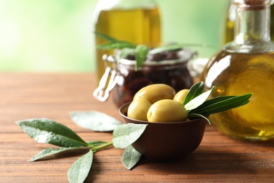 Bowl with olives and bottle of fresh oil on table