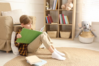 Little boy reading book on floor at home