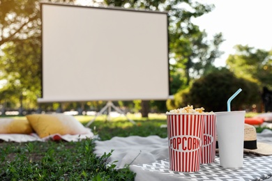 Photo of Popcorn and drink on green grass in open air cinema. Space for text