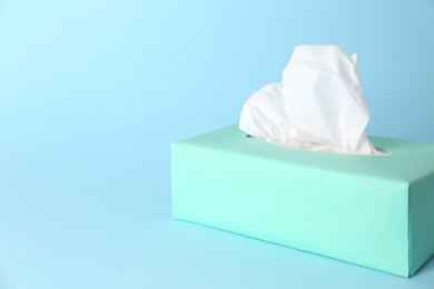 Photo of Box of paper tissues on light blue background. Space for text