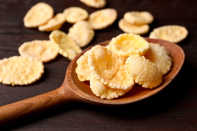 Photo of Spoon of tasty crispy corn flakes on wooden table, closeup