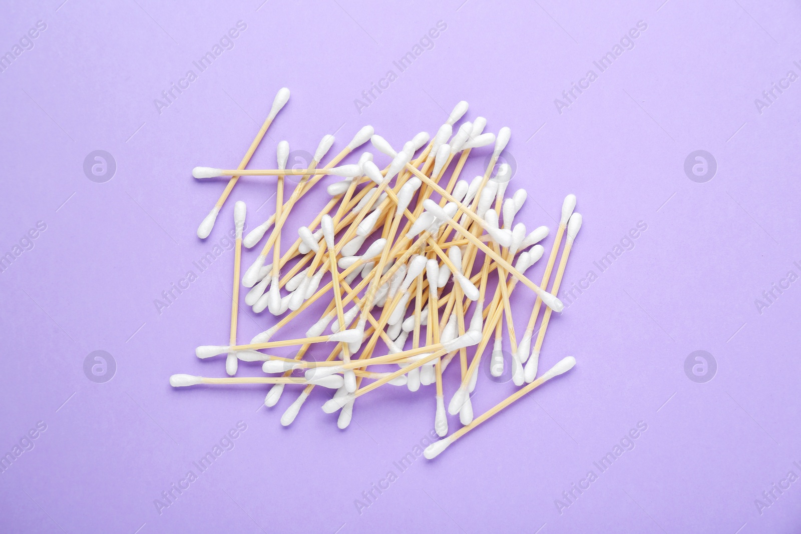 Photo of Wooden cotton buds on violet background, flat lay