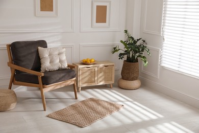 Photo of Stylish rug on floor near armchair in room