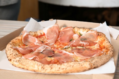 Photo of Tasty Italian oven baked pizza in delivery box on table