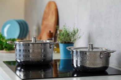 Photo of Pots with lids on cooktop in kitchen. Cooking utensils