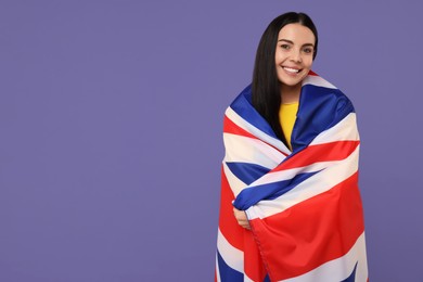 Photo of Happy young woman with flag of United Kingdom on violet background, space for text