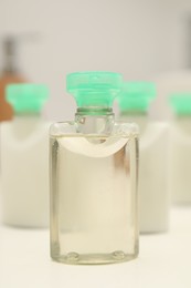 Photo of Mini bottles of cosmetic products on white table, closeup