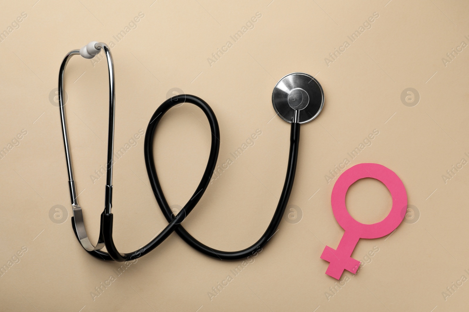 Photo of Female gender sign and stethoscope on beige background, flat lay. Women's health concept