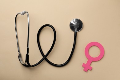 Photo of Female gender sign and stethoscope on beige background, flat lay. Women's health concept