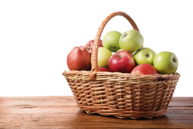 Photo of Fresh red and green apples in wicker basket on wooden table against white background. Space for text