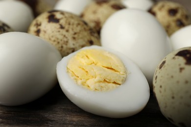 Peeled and unpeeled hard boiled quail eggs on wooden table, closeup