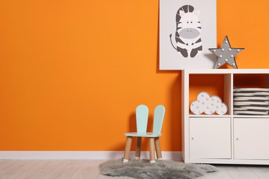 Photo of Beautiful children's room with bright orange wall and furniture, space for text. Interior design