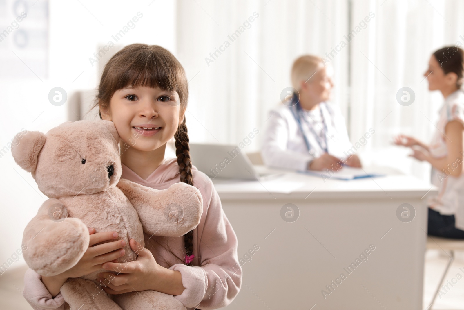 Photo of Adorable child with toy and mother visiting doctor at hospital