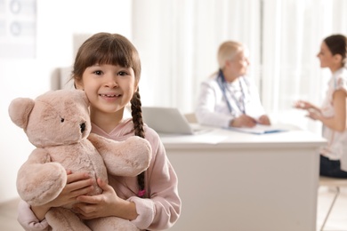 Adorable child with toy and mother visiting doctor at hospital