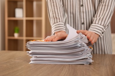 Photo of Woman stacking documents at wooden table indoors, closeup