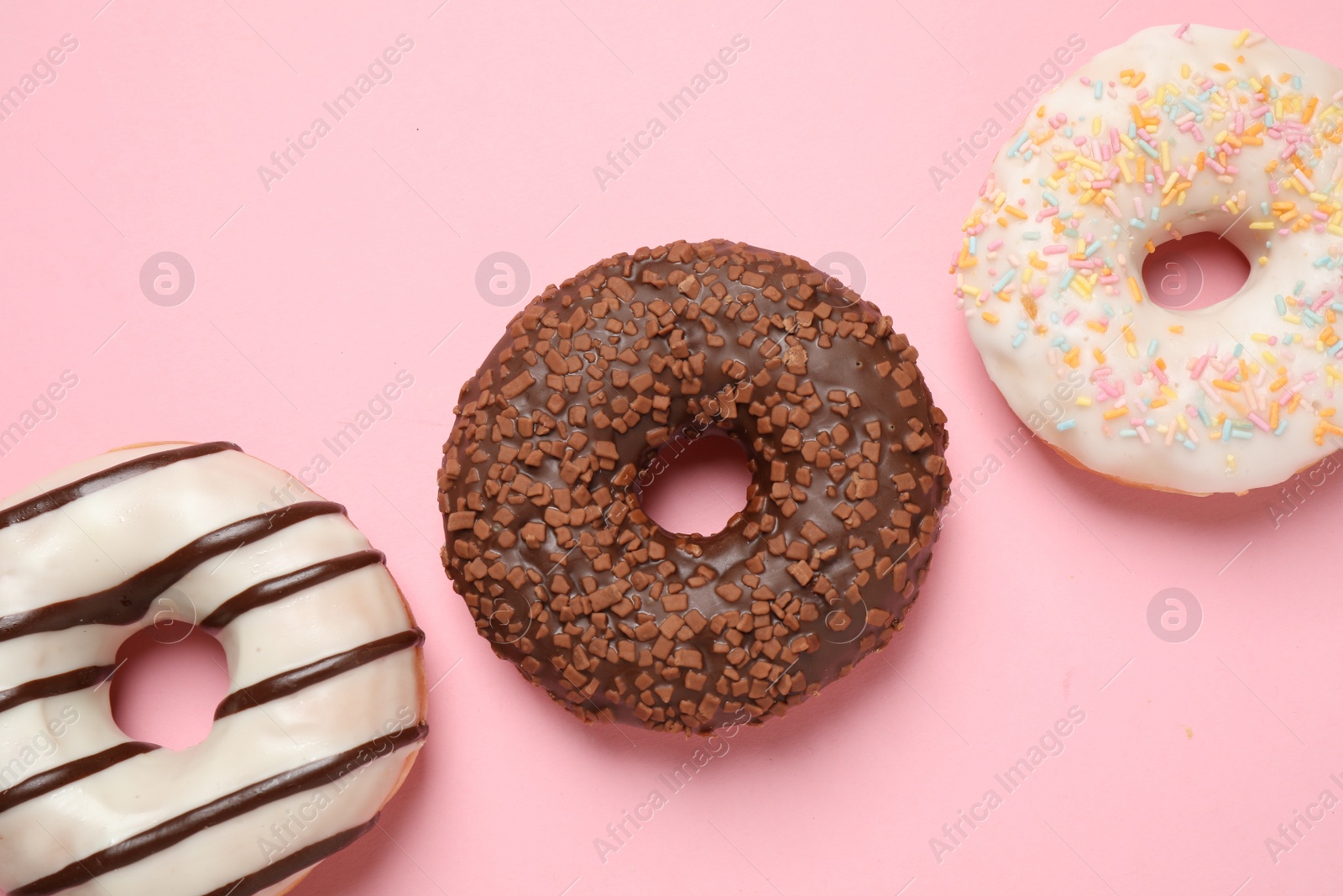 Photo of Delicious glazed donuts on pink background, flat lay