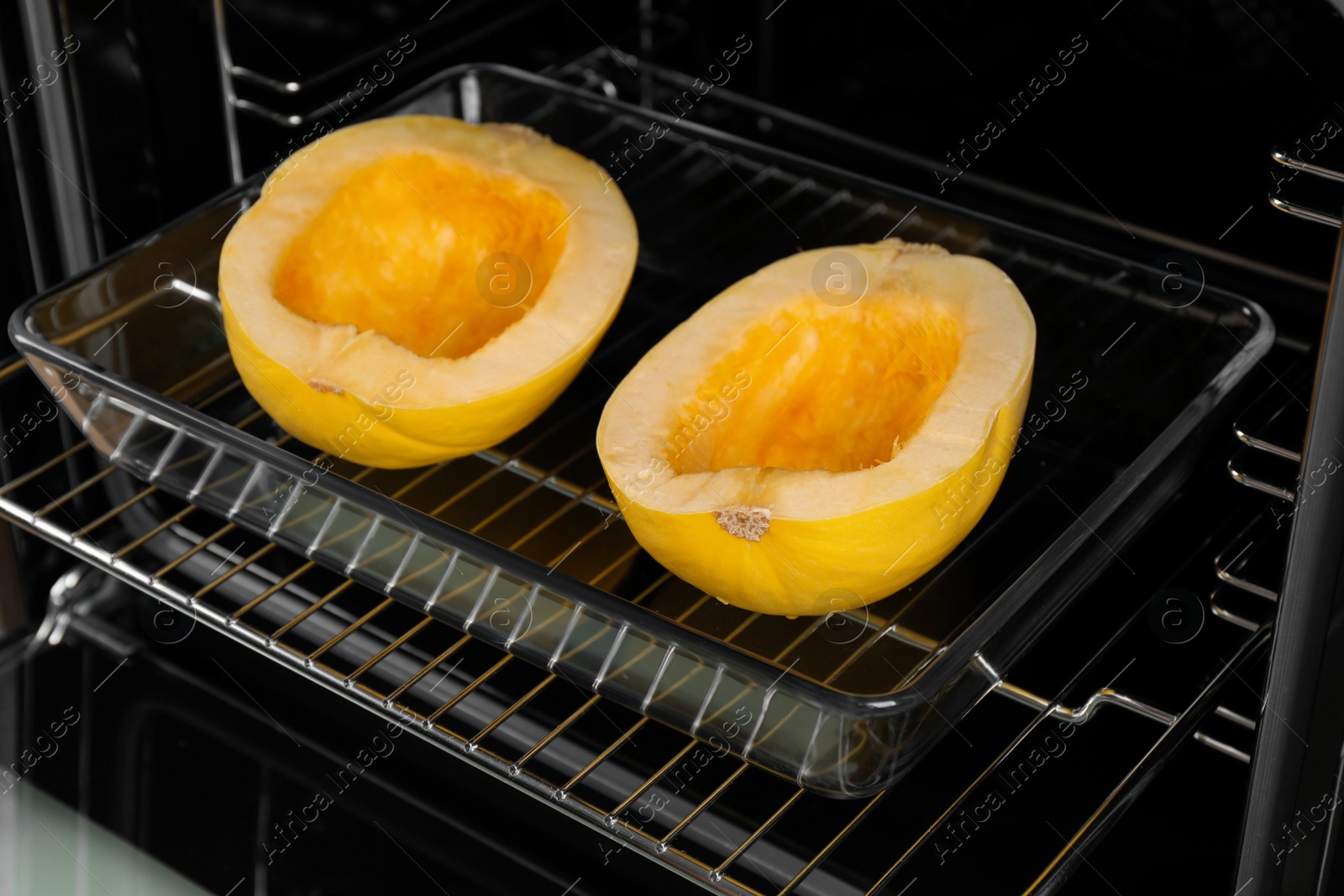 Photo of Baking dish with halves of fresh spaghetti squash in oven