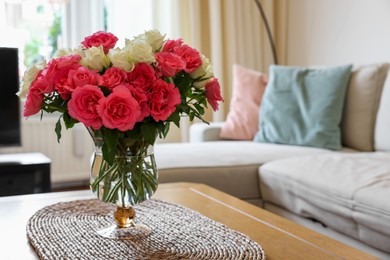 Vase with beautiful bouquet of roses on wooden table at home, space for text