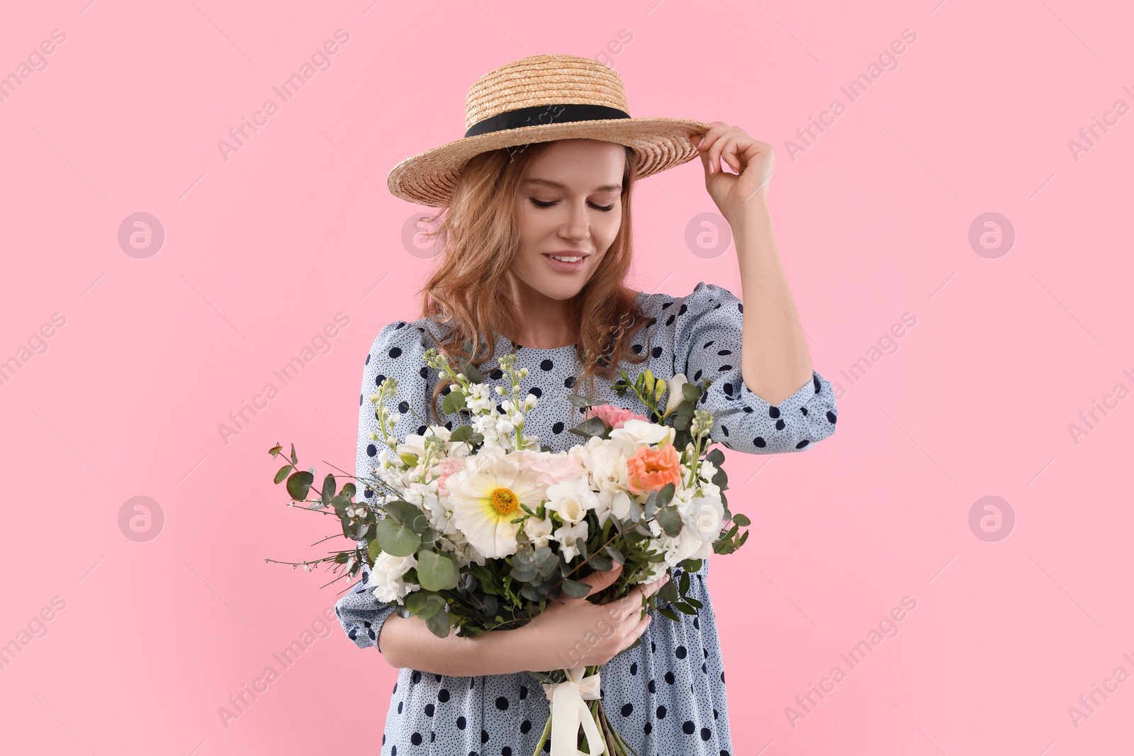 Photo of Beautiful woman in straw hat with bouquet of flowers on pink background
