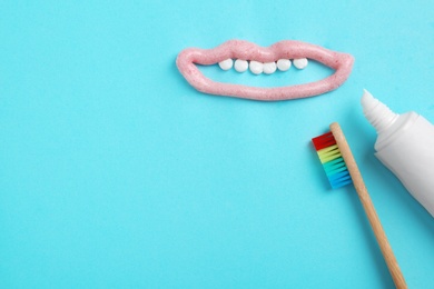 Photo of Mouth with teeth made of paste, tube and brush on color background, flat lay. Space for text