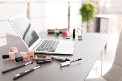 Photo of Makeup products for woman and laptop on table