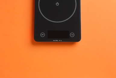 Photo of Modern digital kitchen scale on orange background, top view. Space for text
