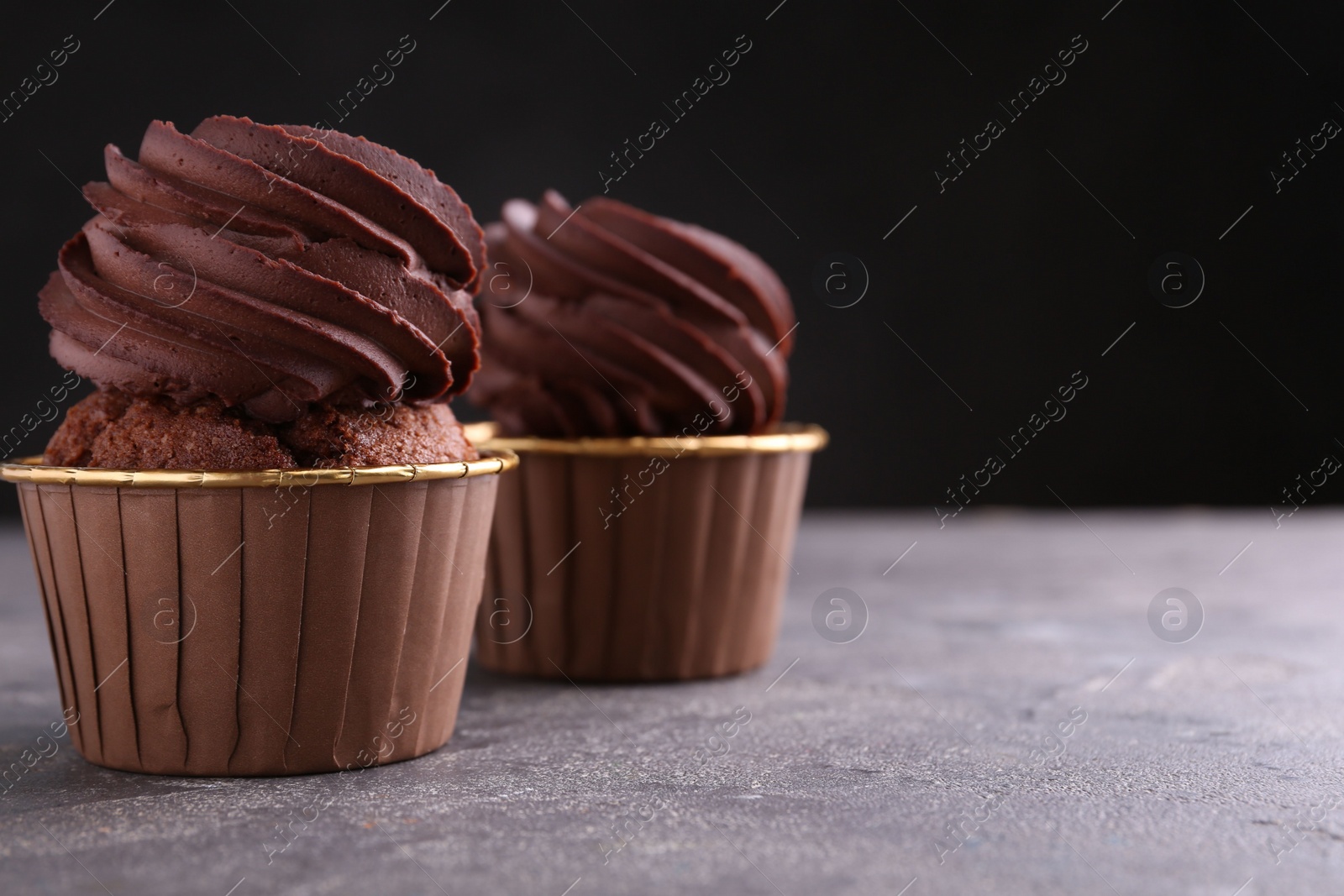 Photo of Delicious chocolate cupcakes on grey textured table, closeup. Space for text