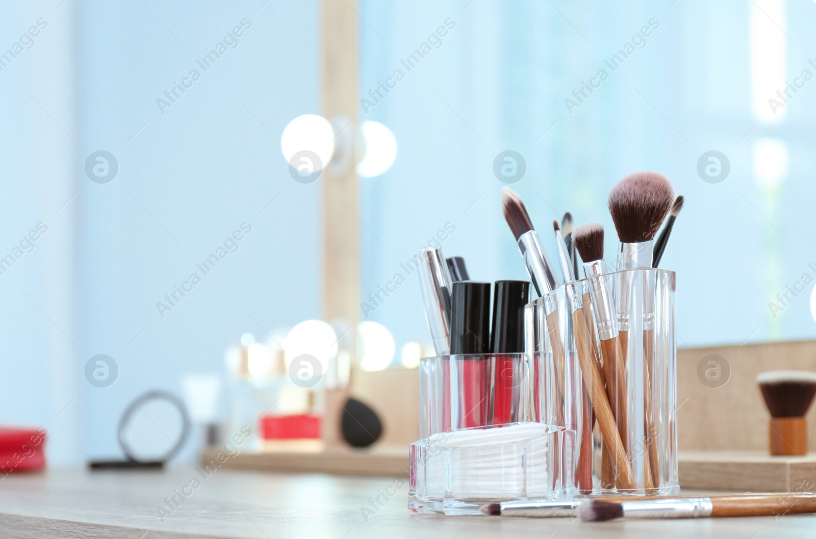 Photo of Organizer with cosmetic products for makeup on table near mirror. Space for text