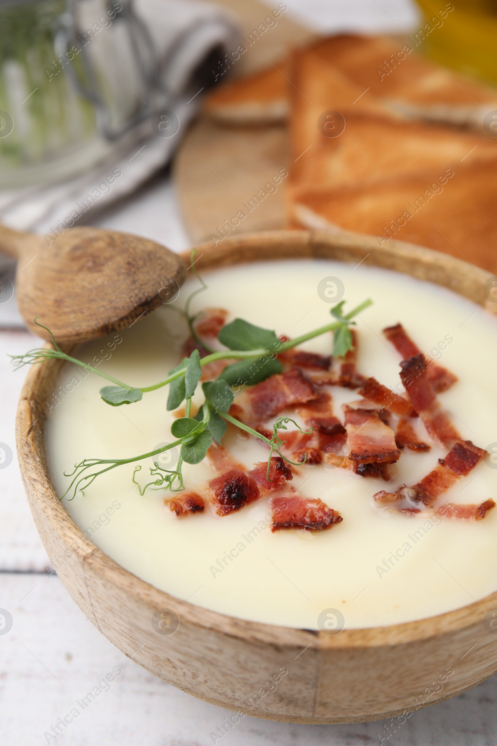 Photo of Delicious potato soup with bacon and microgreens in bowl served on table, closeup